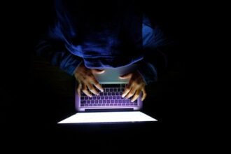 Hooded hacker silhouette with binary code background